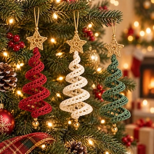 May include: Three spiral-shaped Christmas tree ornaments made of crocheted yarn in red, cream, and dark green. Each ornament features a gold-colored crocheted star at the top and a small gold bead at the bottom, suspended by a gold hanging loop.