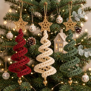 May include: Three hanging Christmas tree ornaments made of crocheted yarn in red, cream, and dark green. Each spiral-shaped tree is topped with a gold-colored crocheted star and features a small gold bead at the bottom, suspended by a gold cord.