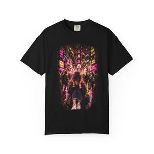 以下が含まれることがあります： MORE MORE NOW、GO FASTER、BUY NOW、BE SEEN、LIVE MORE、NEVER ENOUGH、SHINE BRIGHTERというテキストが表示されたネオンサインがある夜の賑やかな通りに座る人物のグラフィックプリントが施された、黒の半袖Tシャツ。