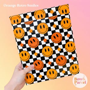 May include: A rectangular poly mailer bag featuring a black and white checkered pattern with orange smiley faces and small orange stars scattered throughout. The text Orange Retro Smiles appears at the top, and Bow & Parcel is at the bottom.