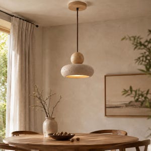 Pode incluir: Uma luminária pendente com uma esfera de madeira lisa sobre um disco texturizado cinza-claro semelhante a pedra. A luminária pende de um fio escuro fino preso a um suporte de teto circular de madeira, emitindo um brilho quente na base.