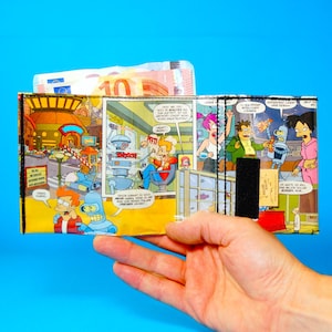 May include: A wallet featuring comic book panels with characters and scenes from the animated series Futurama. The wallet is open, revealing a stack of paper currency. The background is a solid blue.