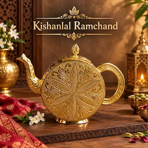 May include: A round gold teapot featuring intricate embossed floral patterns, a curved spout, and a matching lid. The text Kishanlal Ramchand is displayed above the teapot in a decorative font. The teapot has a polished metallic finish.