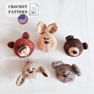 May include: A digital crochet pattern PDF featuring five distinct animal heads: a reddish-brown bear, a tan rabbit, a dark brown bear, a light tan dog with floppy ears, and a grey dog with floppy ears, all with embroidered facial features.