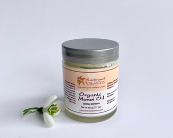 Op de afbeelding: Een klein glazen potje met een zilveren deksel dat een witte, romige substantie bevat. Het potje is gelabeld met "Scentimental Creations Organic Monoi Oil Tahitian Gardenia Net wt 60 g (2.1 oz) www.scentimentalcreations.com".