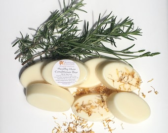 May include: Five white oval-shaped bars of healthy hair conditioner with rosemary sprigs and dried calendula petals scattered around. The label on one bar reads "Healthy Hair Conditioner Bar" with the brand name "Sustainable Creations".