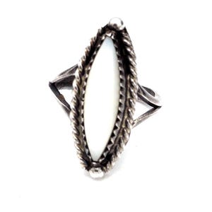 May include: A silver ring featuring a central marquise-shaped white stone inlay. The stone is surrounded by a twisted rope-style metal border and a serrated edge. The band of the ring splits into two thin, plain silver arms on each side.