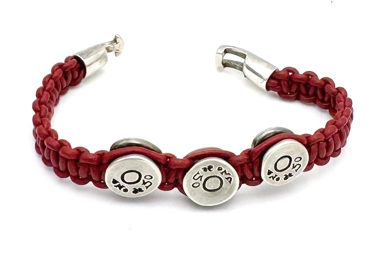May include: Red leather bracelet with three silver round charms that say "OMA" on them.