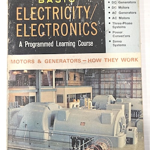 May include: A vintage paperback book titled Basic Electricity/Electronics: A Programmed Learning Course, Volume 5. The cover features a black and white industrial photograph of large grey electrical generators and a red mobile cable reel cart.