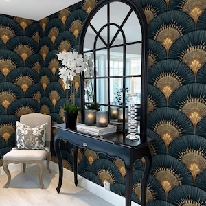 May include: A black arched window-pane mirror sits on a black console table against dark teal and gold fan-patterned wallpaper. A white orchid in a black pot, two glass candle holders, and a stack of books are placed on the table surface.