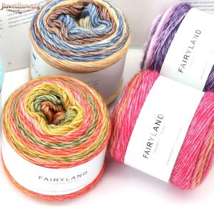 May include: Three round cakes of variegated yarn labeled FAIRYLAND. One cake features blue, tan, and cream tones. Another displays purple, white, and pink hues. The third cake shows a gradient of bright pink, orange, yellow, and green colors.