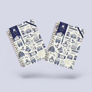 May include: Two spiral-bound notebooks featuring a cream-colored cover with a repeating dark blue pattern of everyday objects including ink bottles, cassette tapes, boomboxes, shoes, and cameras, with a dark blue elastic band and a logo label.