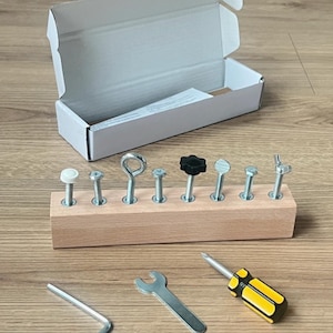 May include: A rectangular wooden block with eight metal bolts and screws inserted into the top, featuring various heads including a white cap, eye bolt, black knob, and wing nut. Includes an L-shaped hex key, a flat wrench, and a yellow screwdriver.