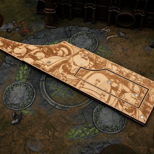 May include: A light-colored wooden game accessory featuring laser-engraved illustrations of armored figures. The elongated, flat piece includes a rectangular cutout section and several small circular metal magnets embedded along the edges.