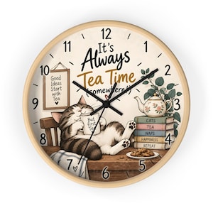 Peut inclure: Une horloge murale ronde avec un cadre en bois clair et un cadran crème. Le texte indique It's Always Tea Time (somewhere!), Good Ideas Start with Tea, et une pile de livres marqués Cats, Tea, Naps, Happiness, Repeat. Un chat tient une tasse.