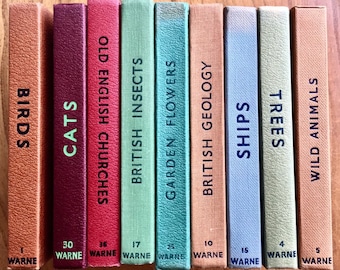 Puede incluir: Un conjunto de diez libros antiguos de tapa dura con cubiertas coloridas y títulos que incluyen "Birds", "Cats", "Old English Churches", "British Insects", "Garden Flowers", "British Geology", "Ships", "Trees", y "Wild Animals". Cada libro tiene un número y "WARNE" impreso en la parte inferior.