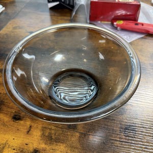 Peut inclure: Un bol mélangeur rond et transparent en verre teinté brun foncé. Le bol présente un intérieur lisse et incurvé ainsi qu'un large bord circulaire, affichant une teinte ambrée profonde qui s'éclaircit vers une nuance translucide sur le bord.