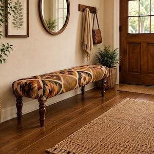 May include: A long, rectangular upholstered bench featuring a geometric pattern in shades of brown, black, and cream. The bench is supported by four dark brown, turned wooden legs and is positioned horizontally in a hallway setting.