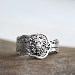May include: A silver ring with a lion head design. The ring is made from a repurposed spoon and has an ornate design.