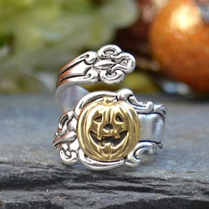 May include: A silver and gold ring with a jack-o'-lantern design. The ring is made from a twisted spoon.