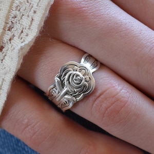 May include: A silver ring with a rose design. The ring is made from a repurposed spoon.