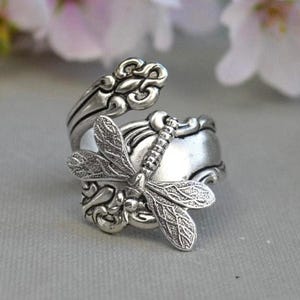 May include: A silver spoon ring with a dragonfly design. The ring is made from a vintage spoon and features intricate details.