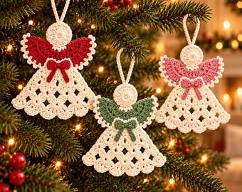 Op de afbeelding: Drie gehaakte engeltjes hangen in een kerstboom. Elk engeltje heeft een crèmekleurig lijfje met een ruitpatroon, een rond hoofdje en een klein strikje in de taille. De vleugels zijn uitgevoerd in de kleuren rood, groen en roze.
