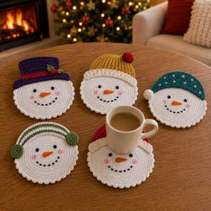 Könnte beinhalten: Fünf runde Häkel-Untersetzer in Schneemannform mit weißen Gesichtern, schwarzen Augen, orangefarbenen Karottennasen und rosa Wangen. Jeder Schneemann trägt ein anderes Accessoire: einen violetten Zylinder, eine gelbe Mütze, eine türkise Kappe, grüne Ohrenschützer oder eine rote Mütze.