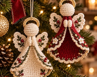 Op de afbeelding: Twee gehaakte engeltjes hangend aan gouden koordjes. Eén engel is crèmekleurig, de andere is dieprood. Beide hebben gouden halo's, geborduurde groene blaadjes, kleine witte bloemetjes en rode besjes langs hun wijd uitlopende rokjes.