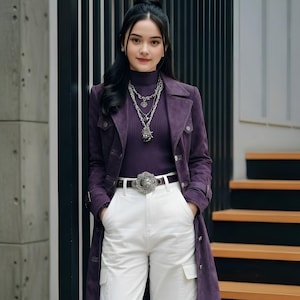 May include: A deep purple long-sleeve mock neck top paired with a matching purple suede-textured trench coat. The outfit includes white cargo trousers with side pockets, a dark belt with a large silver buckle, and layered silver chain necklaces.