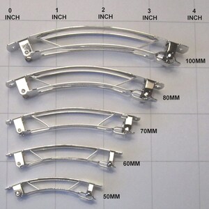 Puede incluir: Cinco pinzas para el pelo de metal plateado de diferentes tama&ntilde;os, que van desde 50 mm hasta 100 mm de longitud. Las pinzas est&aacute;n ordenadas por tama&ntilde;o, con la m&aacute;s peque&ntilde;a en la parte inferior y la m&aacute;s grande en la parte superior.