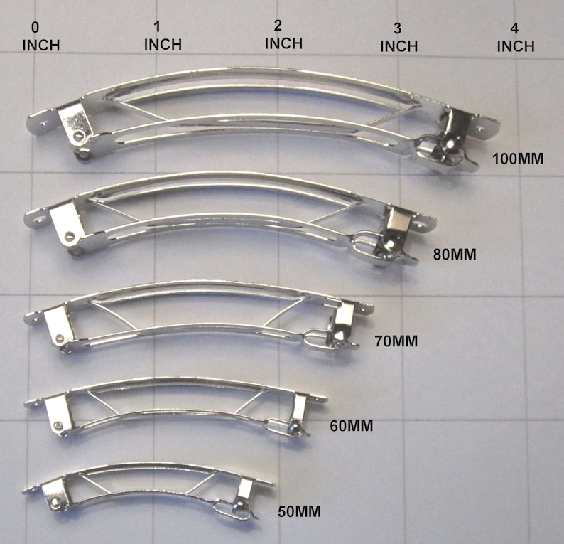 Puede incluir: Cinco pinzas para el pelo de metal plateado de diferentes tama&ntilde;os, que van desde 50 mm hasta 100 mm de longitud. Las pinzas est&aacute;n ordenadas por tama&ntilde;o, con la m&aacute;s peque&ntilde;a en la parte inferior y la m&aacute;s grande en la parte superior.