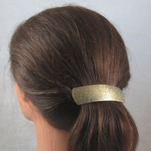 Puede incluir: Un clip para el pelo de metal dorado con un dise&ntilde;o floral. El clip se utiliza para sujetar una coleta.