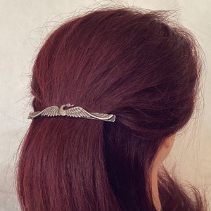 K&ouml;nnte beinhalten: Silberne Haarklammer mit Schwanenmotiv. Die Klammer ist in Form eines Schwans mit ausgebreiteten Fl&uuml;geln. Der Schwan ist nach vorne gerichtet und hat ein detailliertes Design.