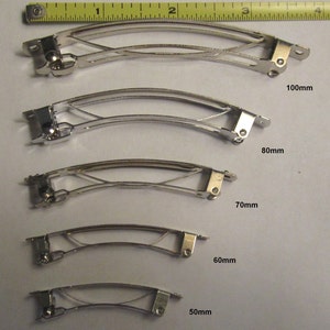 Puede incluir: Cinco pinzas para el pelo de metal plateado de diferentes tama&ntilde;os. Las pinzas est&aacute;n dispuestas de la m&aacute;s grande a la m&aacute;s peque&ntilde;a, siendo la m&aacute;s grande de 10 cm y la m&aacute;s peque&ntilde;a de 5 cm. Todas las pinzas est&aacute;n hechas del mismo metal y tienen un dise&ntilde;o similar.