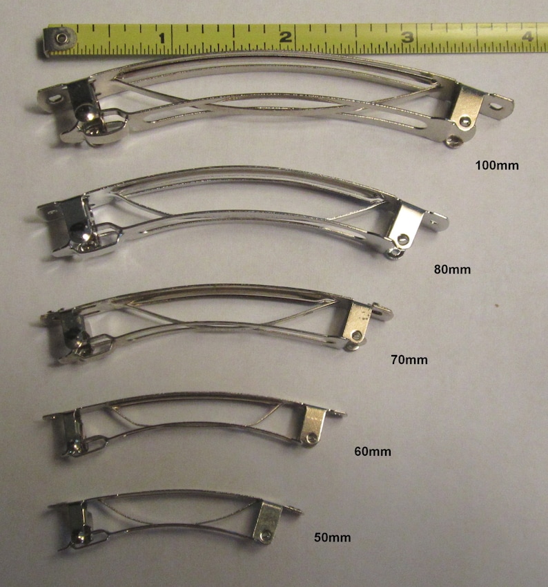 Puede incluir: Cinco pinzas para el pelo de metal plateado de diferentes tama&ntilde;os. Las pinzas est&aacute;n dispuestas de la m&aacute;s grande a la m&aacute;s peque&ntilde;a, siendo la m&aacute;s grande de 10 cm y la m&aacute;s peque&ntilde;a de 5 cm. Todas las pinzas est&aacute;n hechas del mismo metal y tienen un dise&ntilde;o similar.