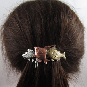 Puede incluir: Una pinza para el pelo con tres dise&ntilde;os de peces. Los peces est&aacute;n hechos de metal y est&aacute;n pintados en tonos cobre, plata y oro. La pinza es una excelente manera de agregar un toque de fantas&iacute;a a cualquier peinado.