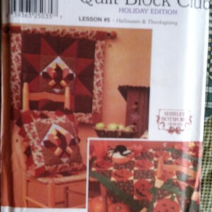 May include: Simplicity Quilt Block Club Holiday Edition pattern. The pattern features quilt block designs for Halloween and Thanksgiving. The image shows a finished quilt block, a pillow, and other decorative items.