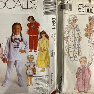 May include: Two sewing pattern packages for children's pajamas. The McCall's pattern is for sizes 10-12 and features a Raggedy Ann and Andy theme. The Simplicity pattern features a variety of styles with floral and polka dot prints.