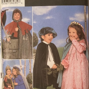 May include: Simplicity Costumes sewing pattern number 5883 for children's costumes. The pattern includes three costumes: a knight, a princess, and a prince. The knight costume features a red cape and chainmail armor. The princess costume features a pink dress with a white veil. The prince costume features a black cape and a white shirt.