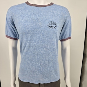 May include: A light blue heathered ringer t-shirt with dark brown trim on the collar and sleeve cuffs. The chest features a circular logo with the text "LARSEN PHYSICAL THERAPY, INC." surrounding a stylized human figure graphic in dark blue ink.