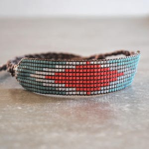 Puede incluir: Pulsera de cuentas hecha a mano con diseño de corazón. La pulsera está hecha con pequeñas cuentas de colores en tonos rojo, turquesa, blanco y gris. Tiene un diseño tejido y un cierre de nudo corredizo para un ajuste ajustable.