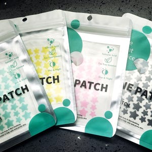 Op de afbeelding: Vier hersluitbare zakjes met stervormige acne-pleisters in de kleuren groenblauw, geel, roze en grijs. Elk zakje bevat de tekst ACNE PATCH, PIMPLE PATCH, Salicylic Acid, Tea Tree Essence en Day & Night, met een doorzichtig venster voor de stickers.