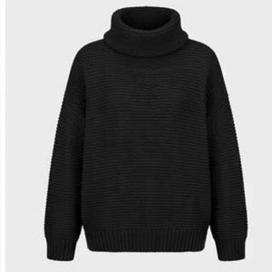 Puede incluir: Un suéter negro de manga larga con una textura de punto grueso en todo el cuerpo y las mangas. La prenda presenta un cuello alto ancho y prominente, además de puños y dobladillo acanalados que proporcionan un ajuste estructurado y definido.