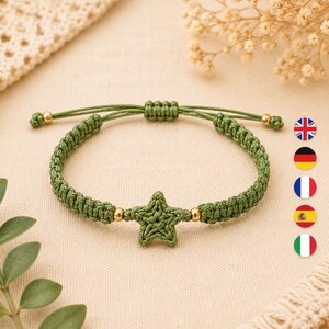 May include: An olive green macrame bracelet featuring a central crocheted star charm. The band is constructed from braided cord with two small gold-toned metallic beads flanking the star and two additional beads at the adjustable sliding closure.