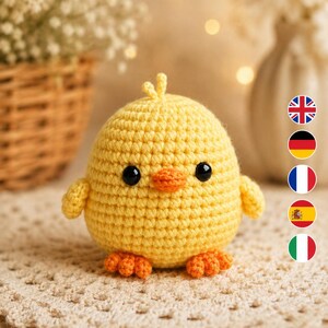 May include: A small, round, yellow crocheted chick toy featuring a textured yarn surface, two black plastic safety eyes, a small orange crocheted beak, and two orange crocheted feet. The chick has a tiny tuft of yellow yarn on its head.