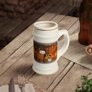 May include: A white ceramic beer stein featuring a graphic of a cartoon dog sitting in a burning room with the text This is fine and a twenty-sided die in the foreground. The stein has a textured rim and base with thin gold trim accents.