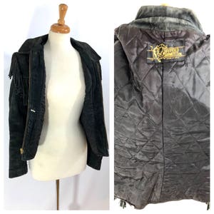 May include: Black suede fringe jacket with a zipper closure and a quilted lining. The jacket has a label that reads "Branded Garments Made in U.S.A."