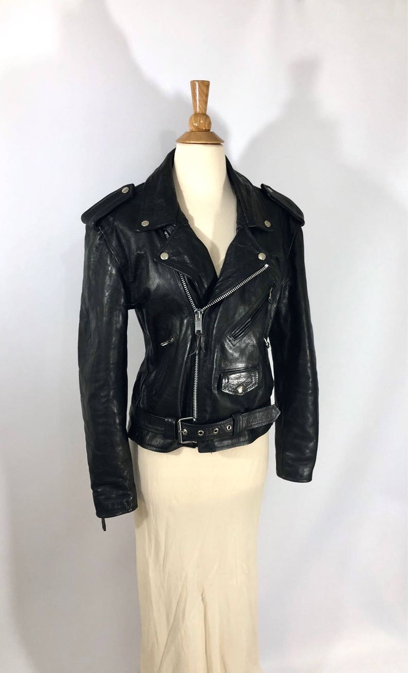 May include: Black leather motorcycle jacket with a zipper closure, a belt, and silver hardware.