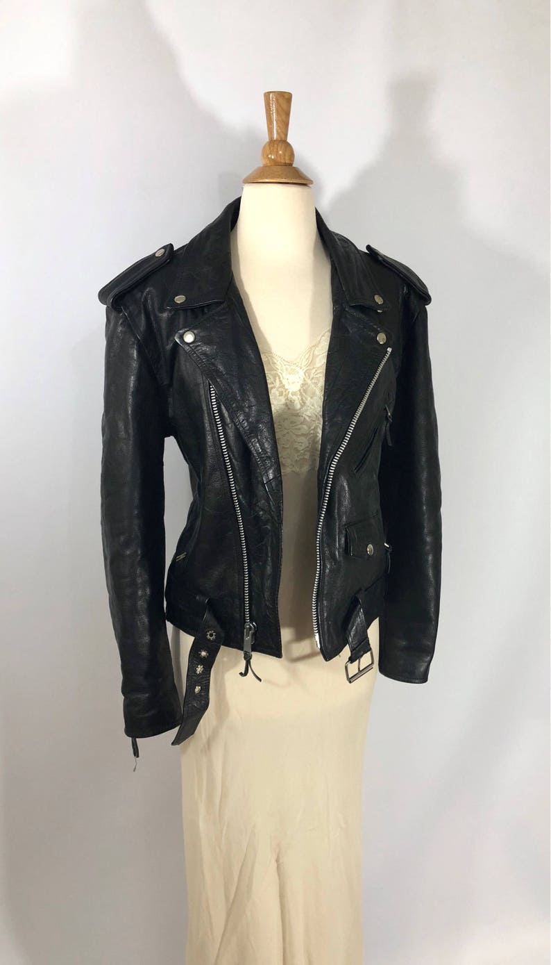 May include: A black leather motorcycle jacket with a zipper closure and a belt at the waist.